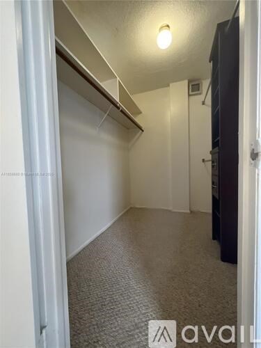 A hallway with a carpeted floor and white walls.