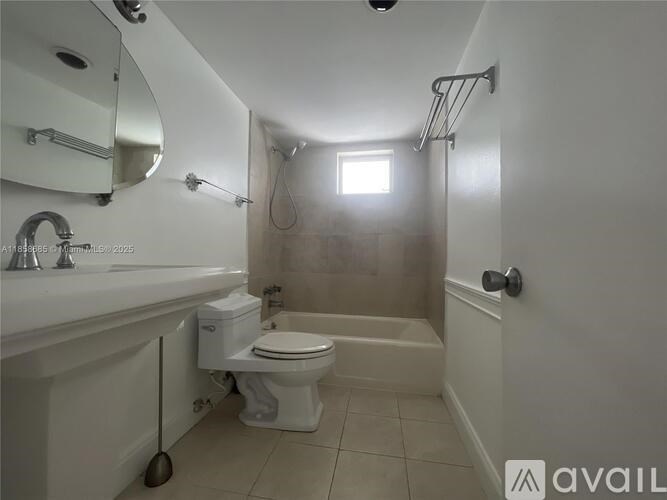 A white toilet is in a small bathroom with a white tub and sink.