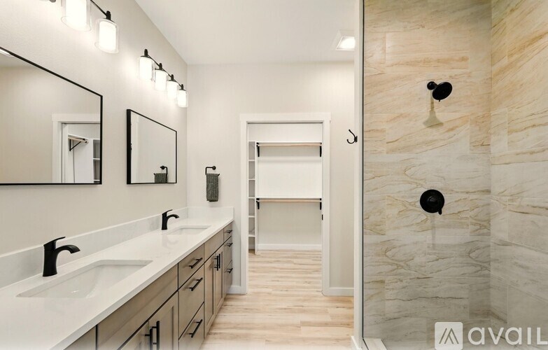 A bathroom with a marble shower wall and a vanity with two sinks.