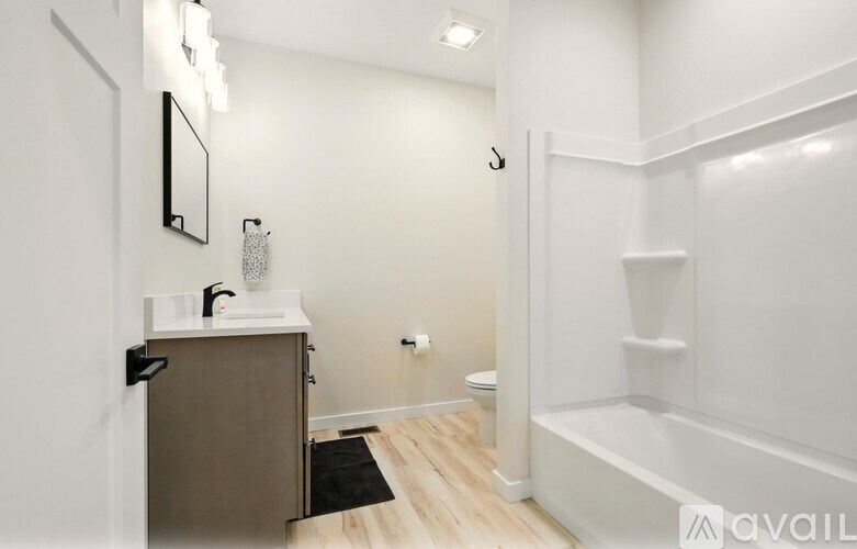 A bathroom with a white tub, sink, and mirror.