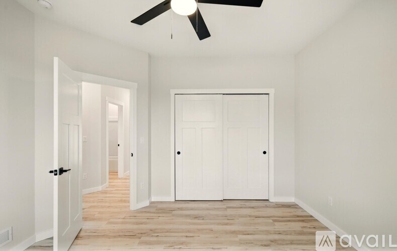 A room with a ceiling fan and two doors.