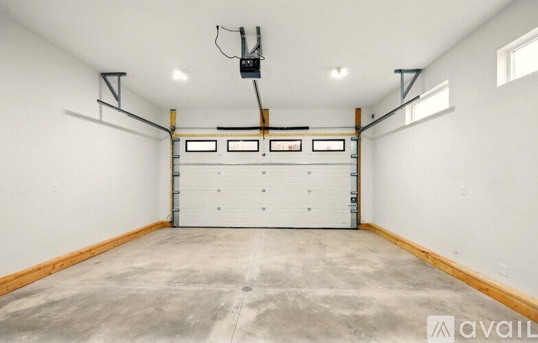 A large empty garage with a white door and a black ceiling fan.
