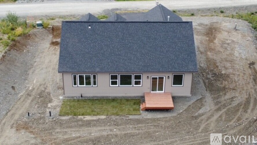 A house with a grey roof and a brown bench in front of it.