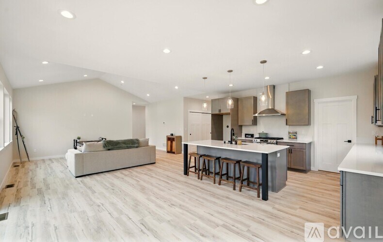 A spacious open plan living and kitchen area with a grey sofa and wooden flooring.