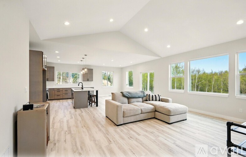 A spacious living room with a kitchen area in the background.