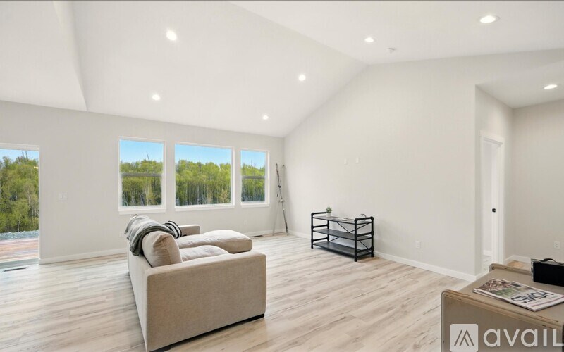 A spacious living room with a couch, a coffee table, and a view of trees through the windows.