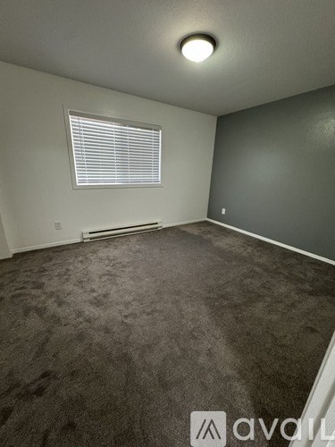 A room with a carpeted floor and a window with blinds.