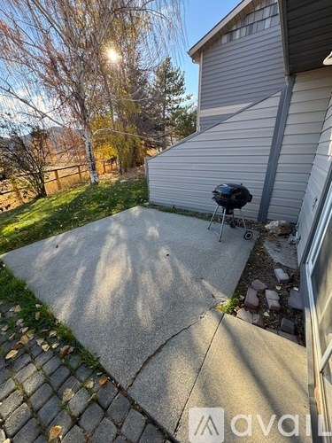 A patio area with a grill and a house in the background.