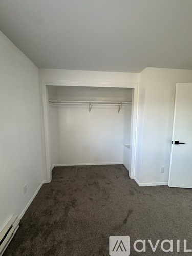 A room with a carpeted floor and a door on the right side.
