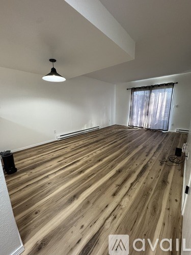 A room with wooden flooring and a single light hanging from the ceiling.