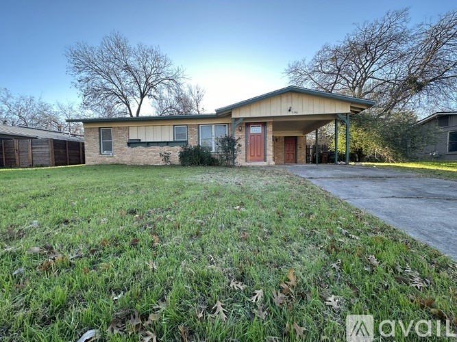 A house with a red door is surrounded by a grassy area.