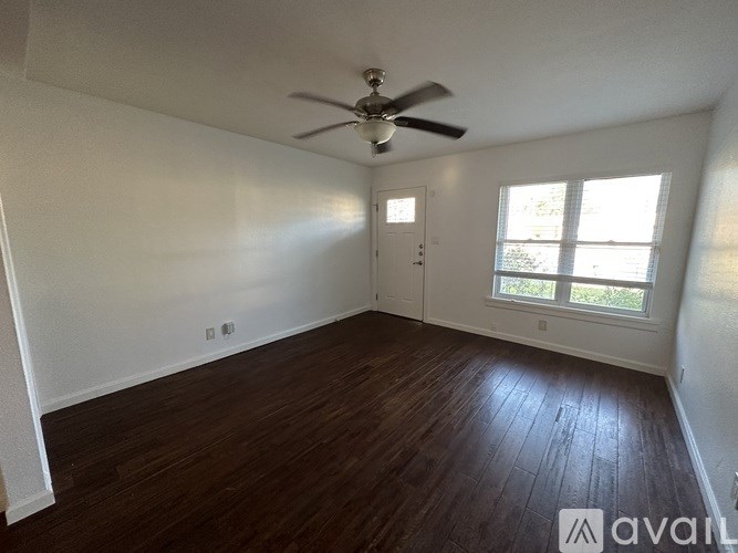 A room with a ceiling fan and wooden flooring.