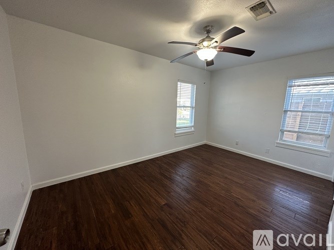 A room with a ceiling fan and wooden flooring.