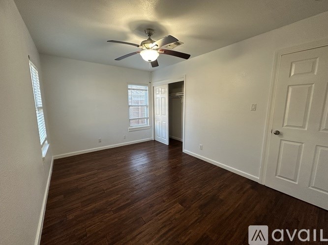 A room with a ceiling fan and wooden flooring.