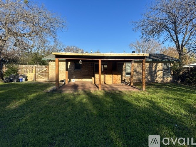 A house with a green roof and a brown wooden exterior is surrounded by a grassy area.