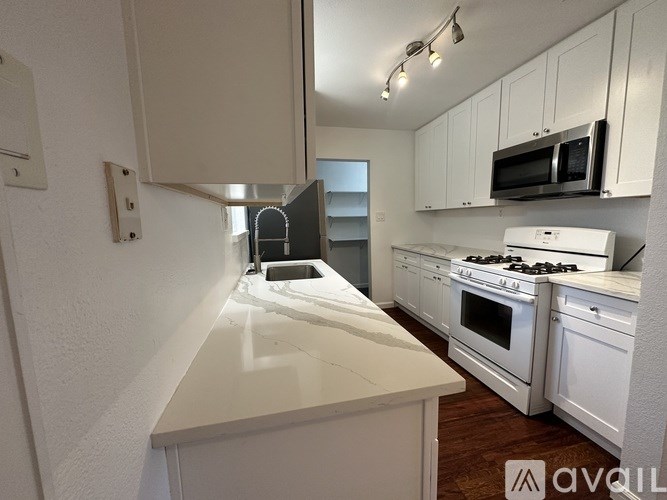 A kitchen with white cabinets and appliances.