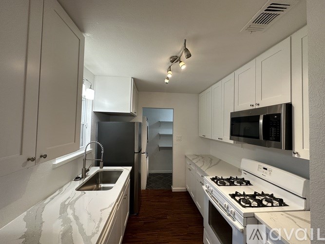 A kitchen with white cabinets and a black refrigerator.