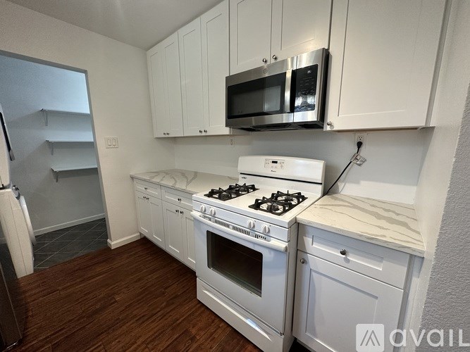 A kitchen with white cabinets and a stove top oven.