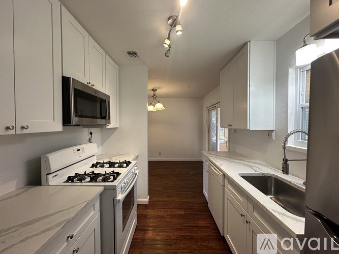 A kitchen with white cabinets and a stove top oven.
