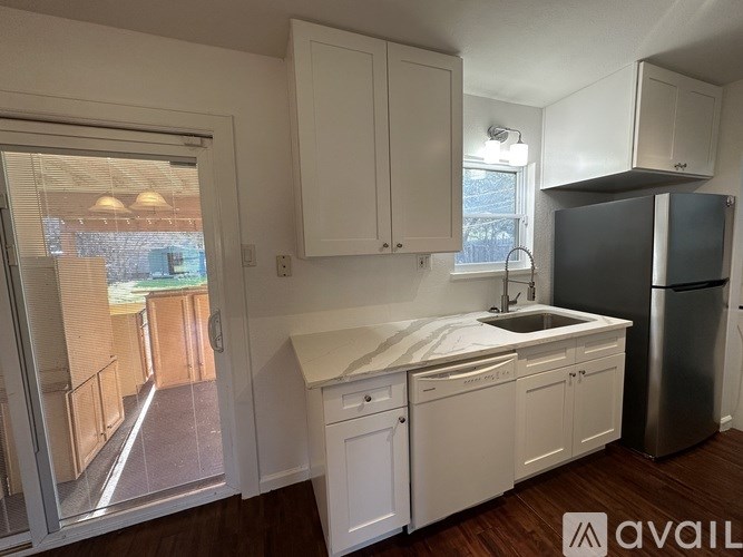 A kitchen with white cabinets and a black refrigerator.