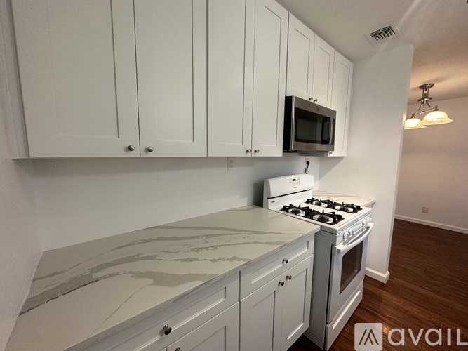 A kitchen with white cabinets and a marble countertop.