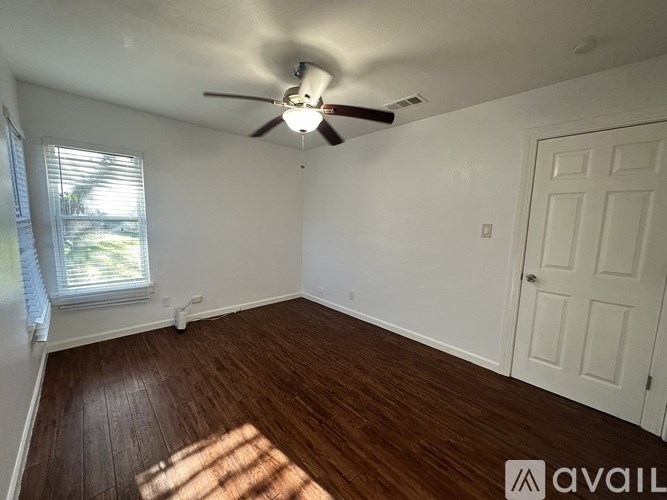 A room with a ceiling fan and wooden flooring.