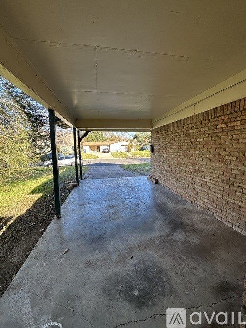 A long concrete walkway with a brick wall on one side and a metal pole on the other.