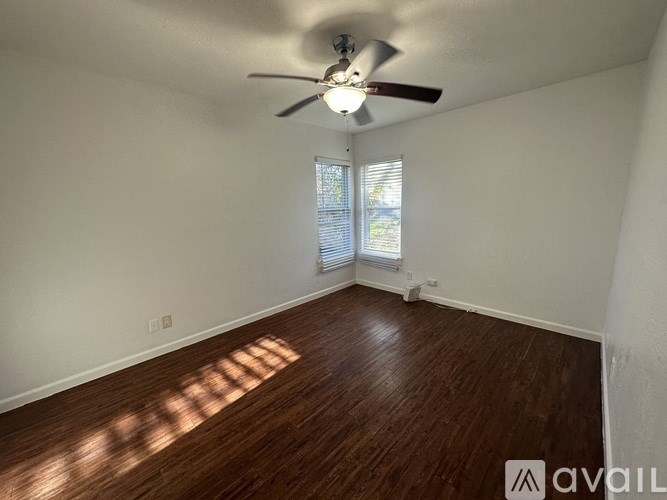A room with a ceiling fan and wooden flooring.