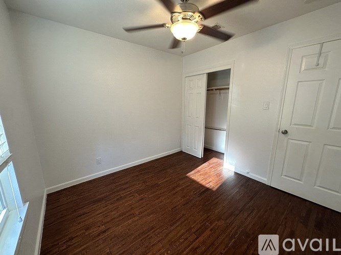 A room with a ceiling fan and wooden flooring.