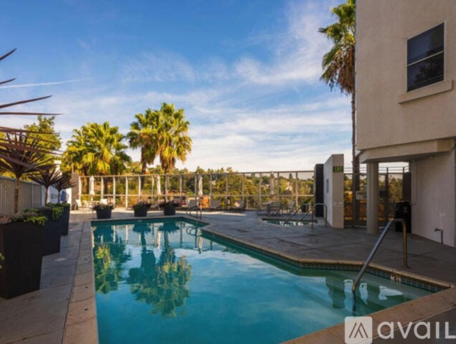 A pool surrounded by palm trees and a building.