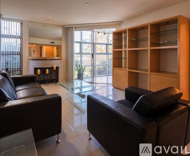 A living room with black leather furniture and a fireplace.