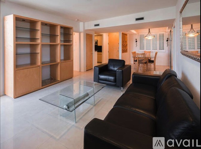 A living room with a black leather couch and a glass coffee table.