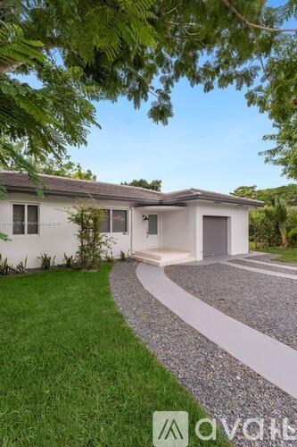 A modern house with a white exterior and a gravel pathway leading to the entrance.
