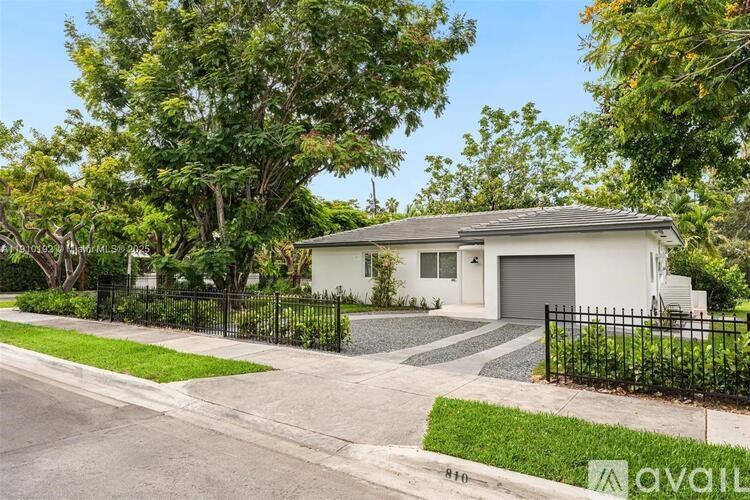 A white house with a black fence is for sale.