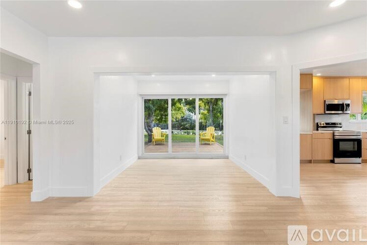 A spacious room with a view of a backyard through a sliding glass door.