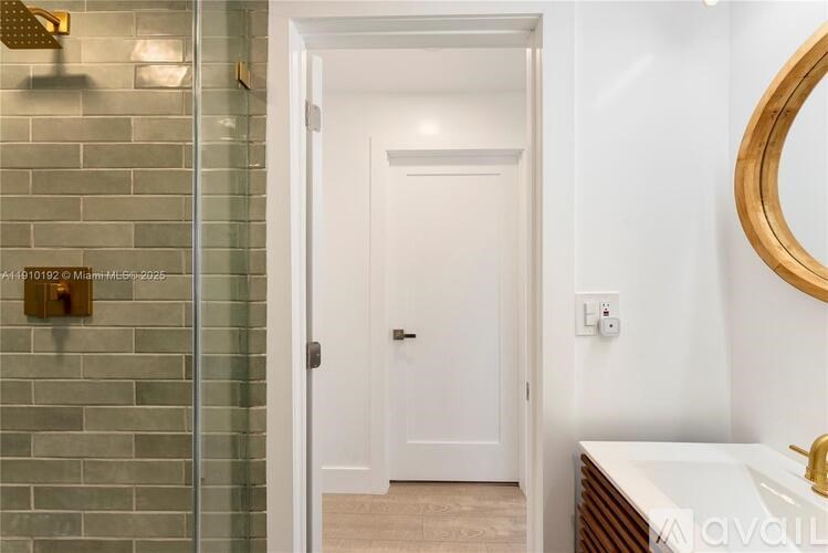 A bathroom with a white door and a gold framed mirror.