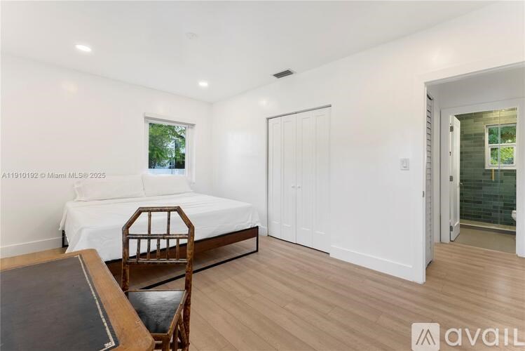 A bedroom with a bed, chair, and wooden floor.