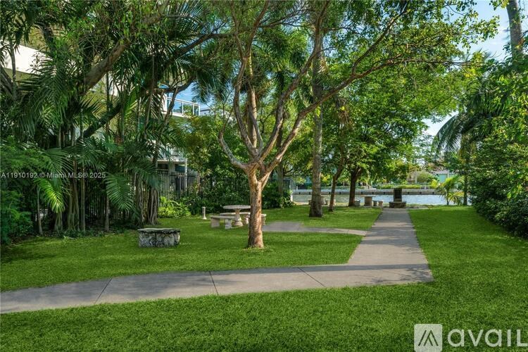 A park with a bench and a tree in the middle of a concrete path.