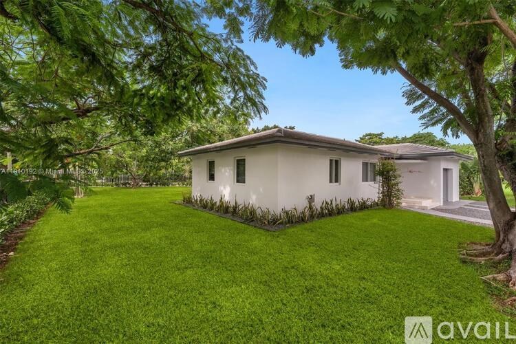 A white house with a green lawn and trees in the background.