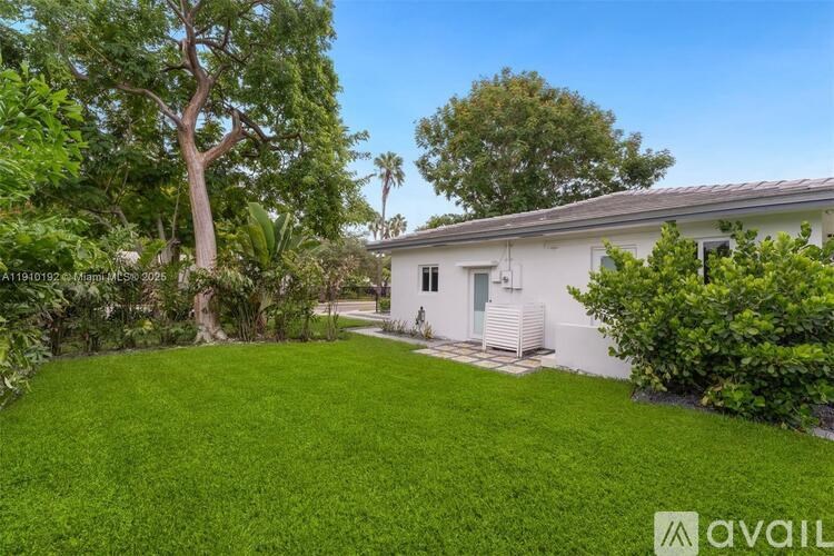 A white house with a green lawn and trees in the background.