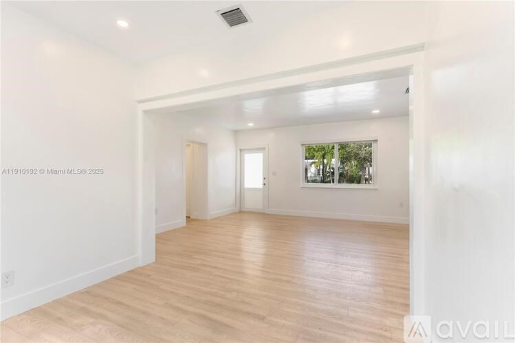 A spacious room with wooden flooring and white walls.
