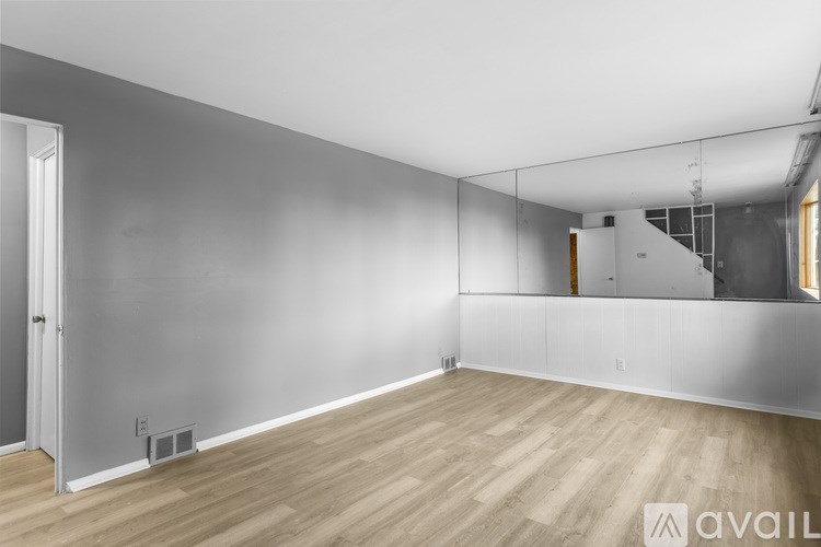 A spacious room with wooden flooring and a grey wall.