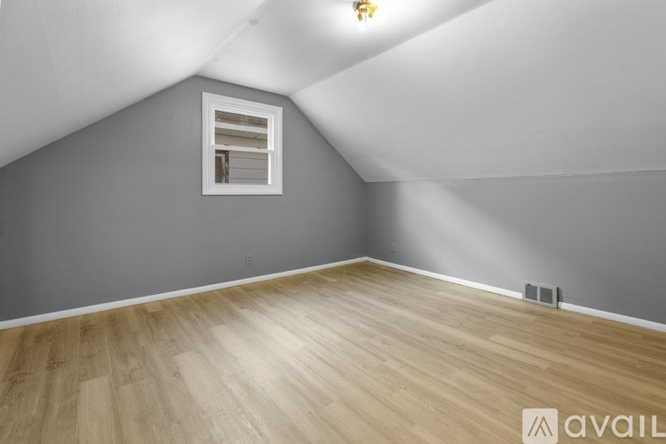 A room with a window and wooden flooring.