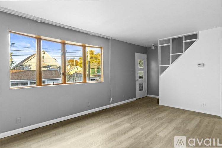 A spacious room with wooden flooring and a staircase to the right.