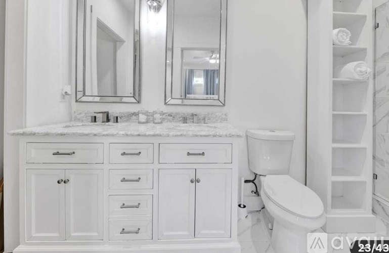 A white bathroom with a toilet and a vanity with drawers.