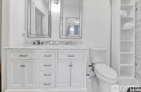 A white bathroom with a toilet and a vanity with drawers.