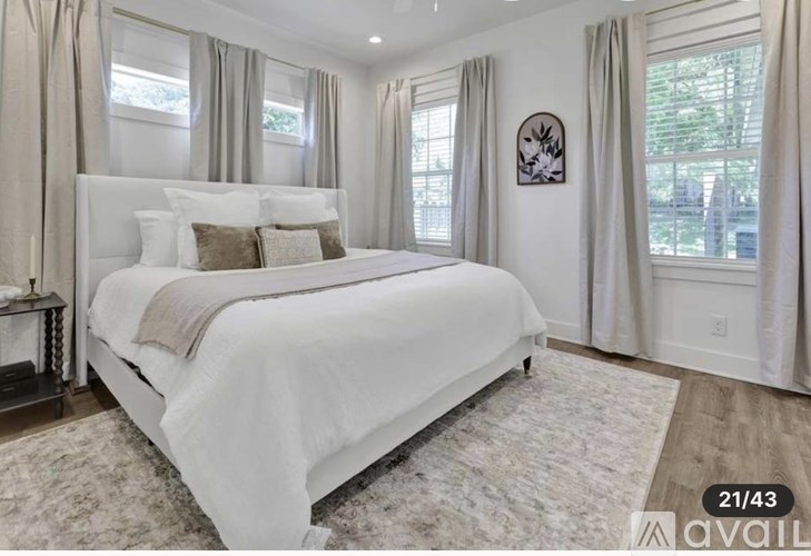 A bedroom with a large bed and a window with curtains.