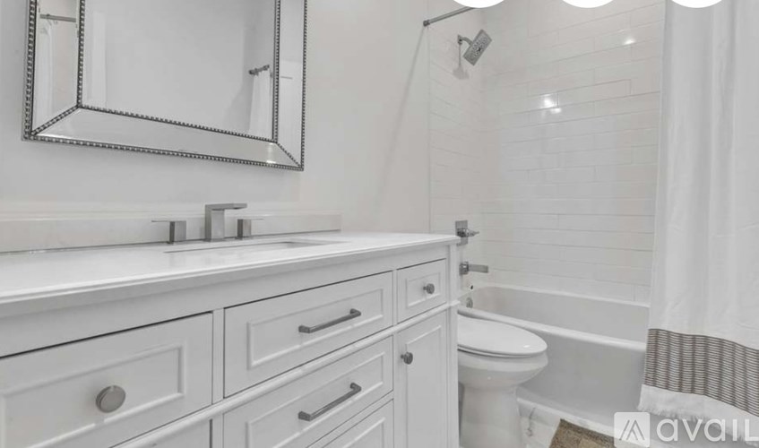A white bathroom with a mirror, sink, and bathtub.