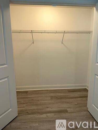 A white closet with a wooden floor and a white door.