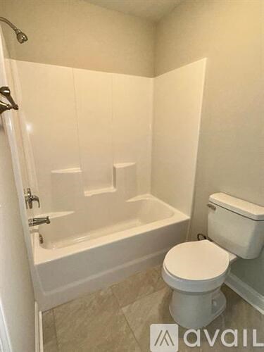 A white toilet sits next to a bathtub in a bathroom.